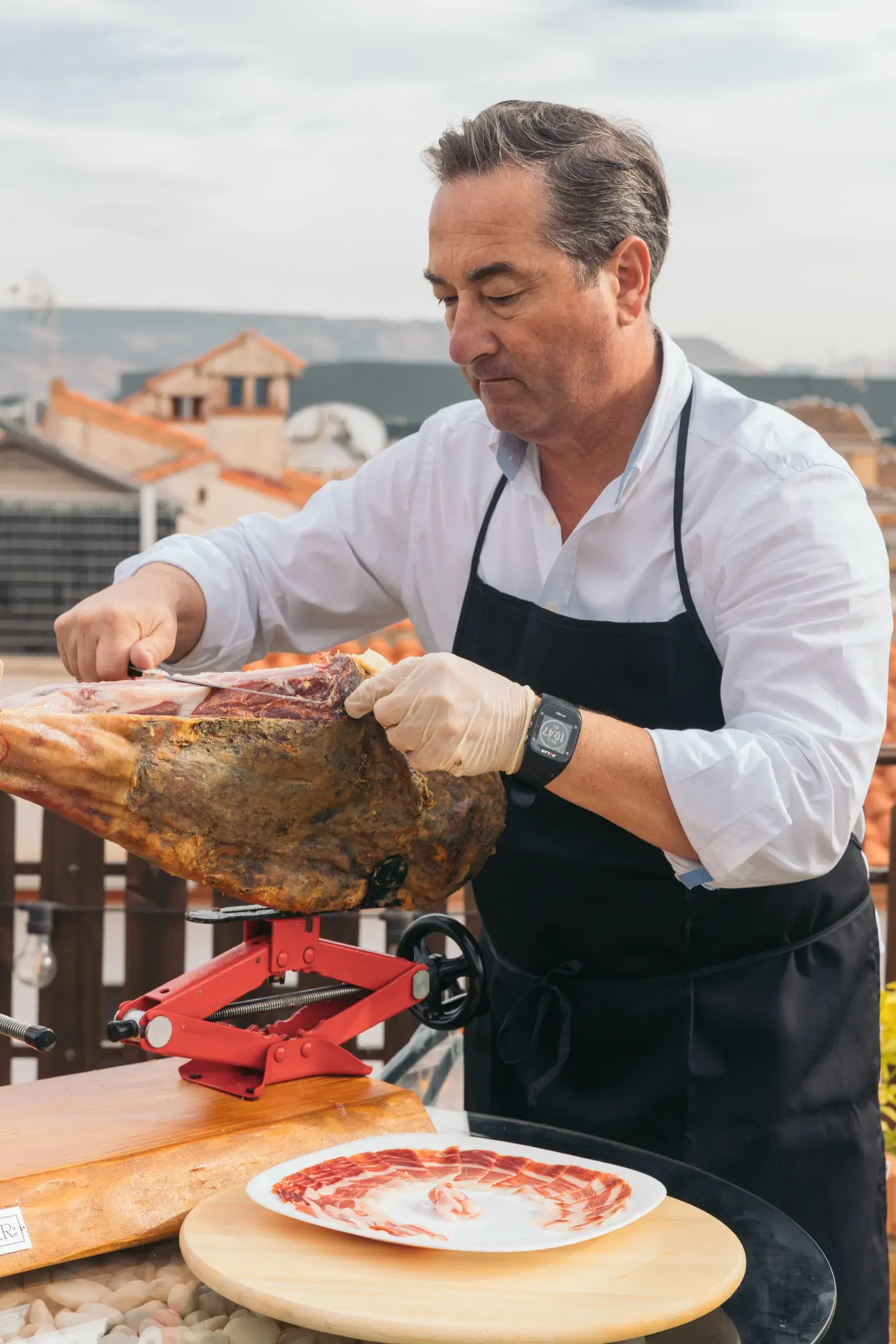 El creador corta el jamón con el plato preparado delante