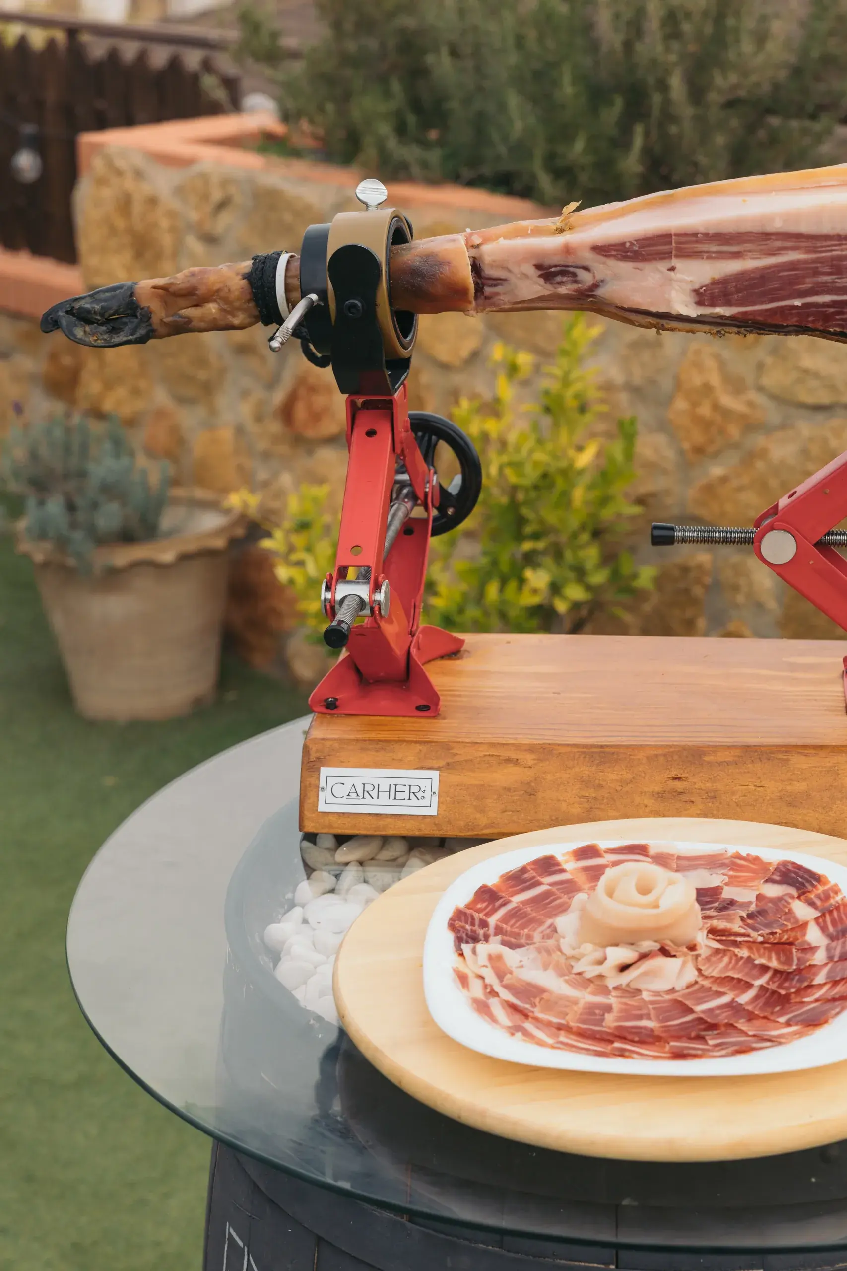 Plato de jamón cortado junto a la anilla y la base del jamonero Carher94